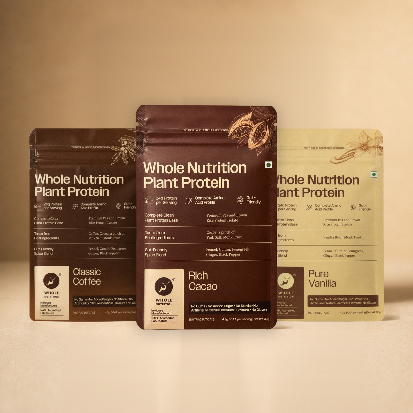 Three Whole Nutrition Plant Protein sachets — Classic Coffee, Rich Cacao and Pure Vanilla — standing side by side on a warm beige surface.