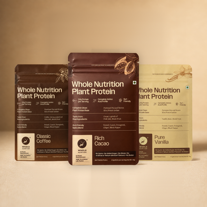 Three Whole Nutrition Plant Protein sachets — Classic Coffee, Rich Cacao and Pure Vanilla — standing side by side on a warm beige surface.