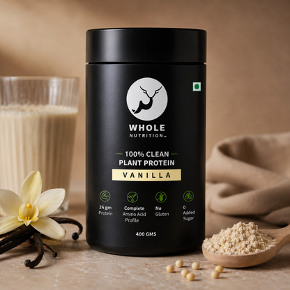 Black container of Whole Nutrition vanilla protein powder with vanilla beans and a scoop of powder on a wooden surface.